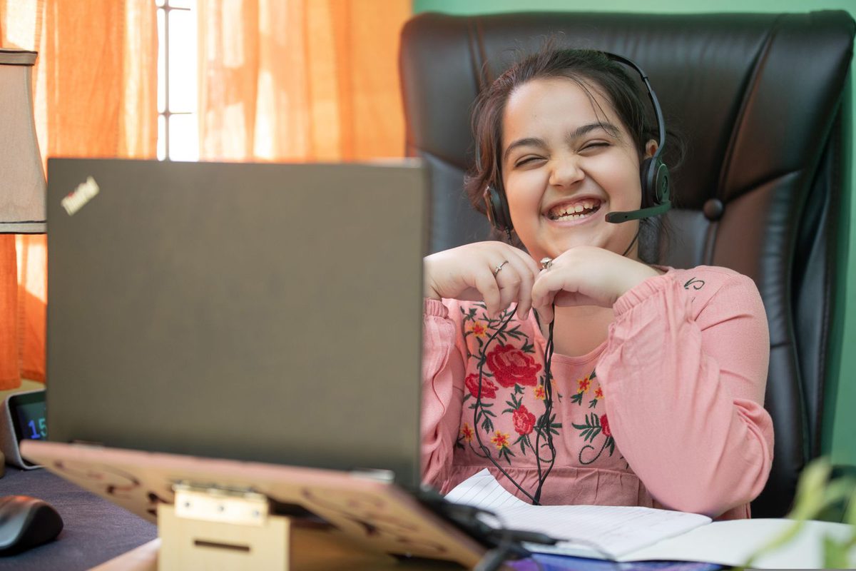 A girl laughing during an online class at home