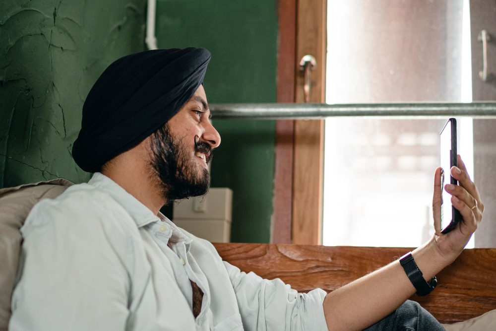 A teacher on a video call from home, smiling at his phone
